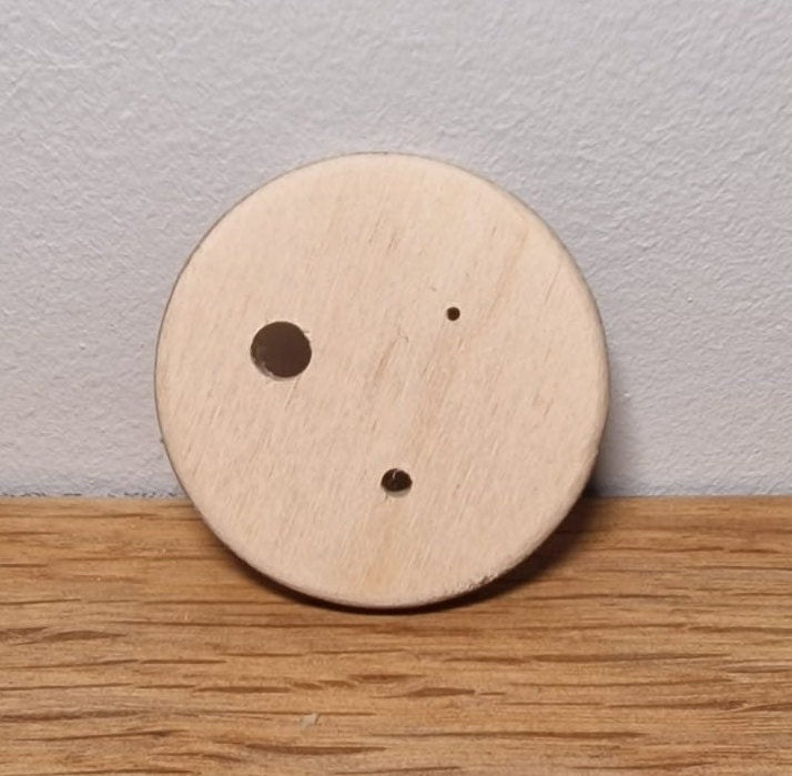 A Plywood Diz, with 3 holes drilled into it.