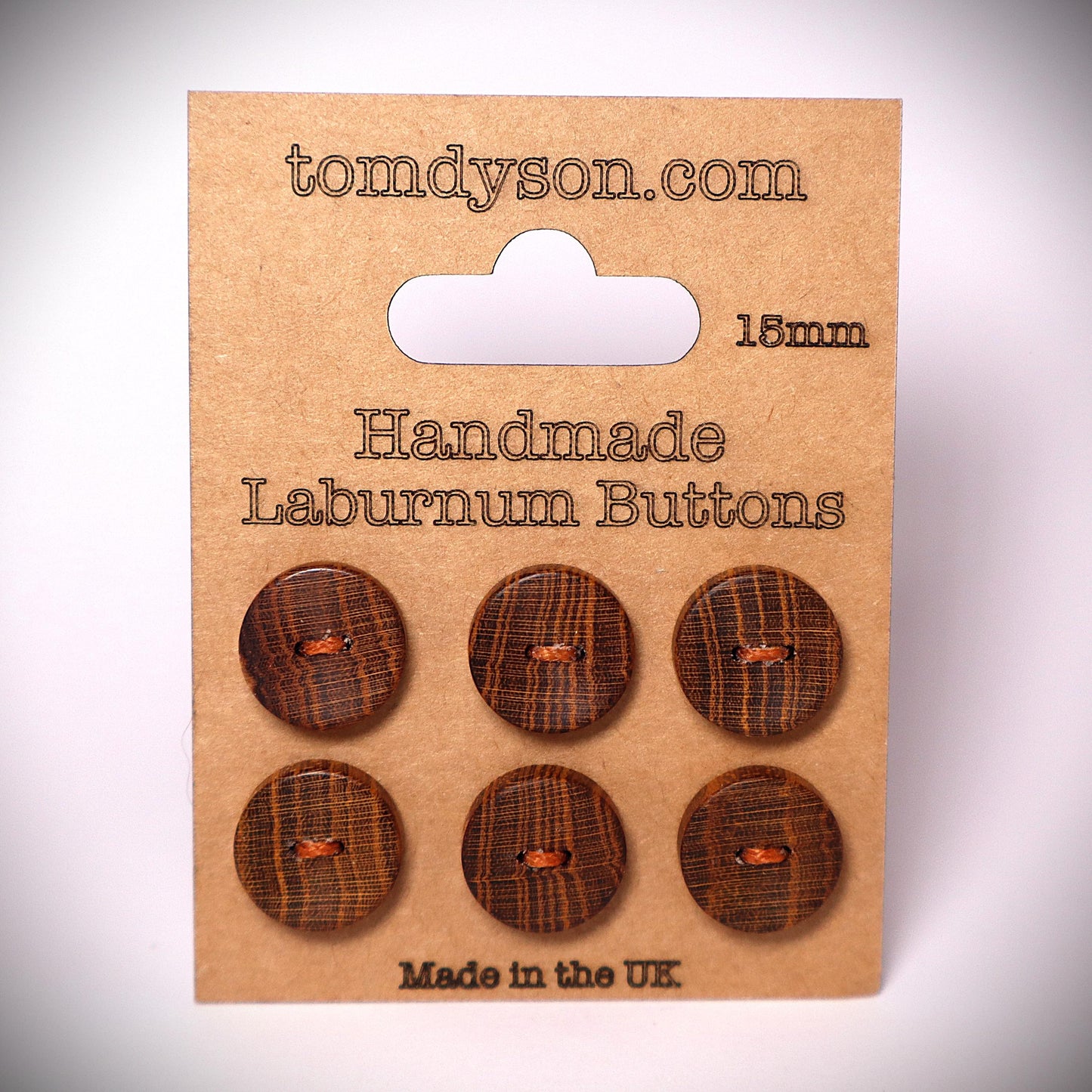 Laburnum 15mm handmade wood buttons. 6 buttons stitched onto a clean brown card. They are brown, with golden growth rings. They are very unique buttons made by Tom Dyson Woodworking. These buttons have 2 holes.